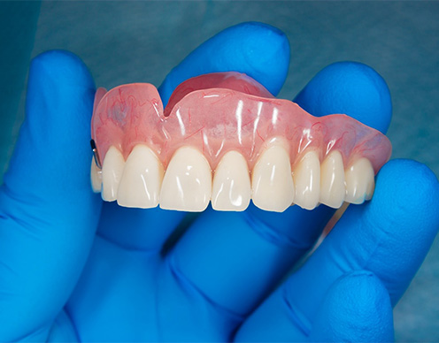 lab tech holding dentures in Randolph