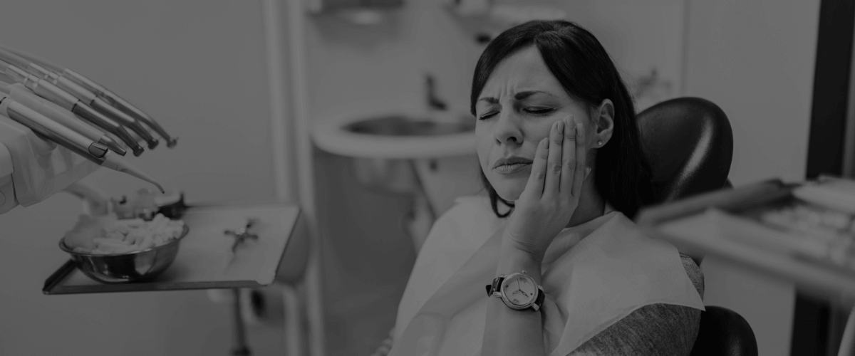 Woman at emergency dentistry appointment holding cheek