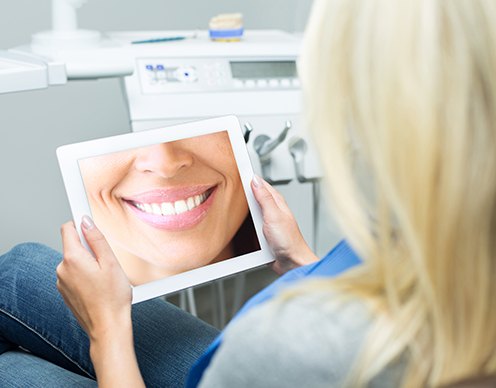 Woman looking at virtual smile design on tablet computer