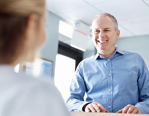 Man giving dental insurance forms to dental team member