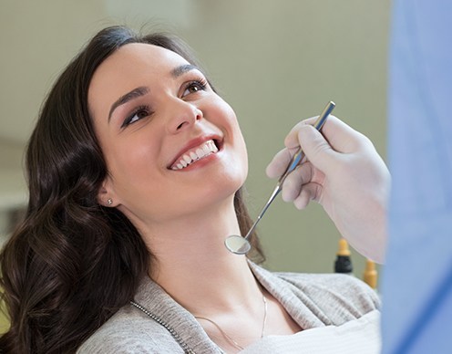 Woman in dental chair smiling at dentist