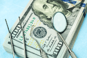 stack of money with dental tools on table