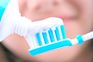 closeup of woman putting toothpaste on toothbrush
