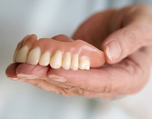 Hand holding a full denture