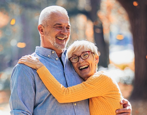 Older man and woman smiling after prettau dental bridge restoration