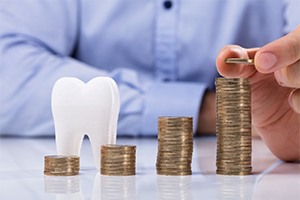 Coins and model tooth symbolizing the cost of dental implants in Randolph