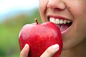 Closeup of patient with dental implants in Randolph eating an apple