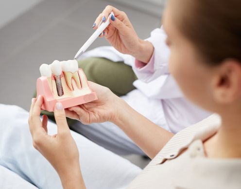 Dentist showing patient dental implant model