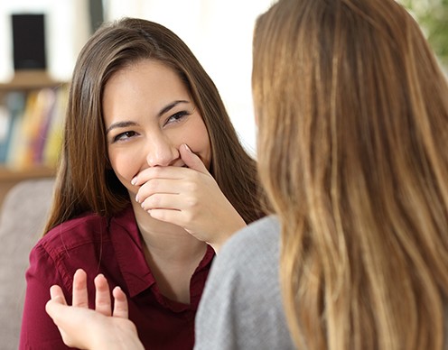Woman in need of halitosis treatment for bad breath covering her mouth