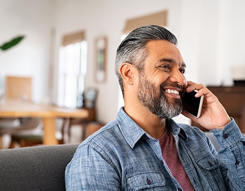 Man smiling while talking on phone at home