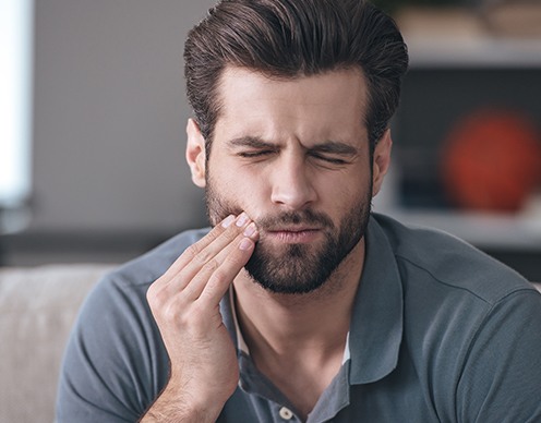 Man in need of tooth extraction holding jaw in pain