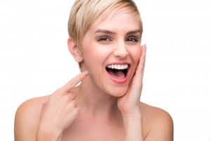 woman smiling pointing at perfect teeth