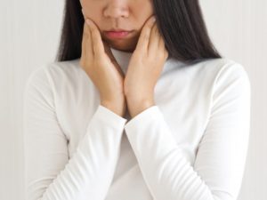 Woman with jaw pain, should visit dentist for TMJ therapy