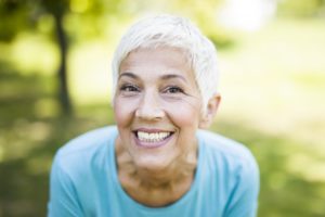 woman grinning with dental implants after menopause
